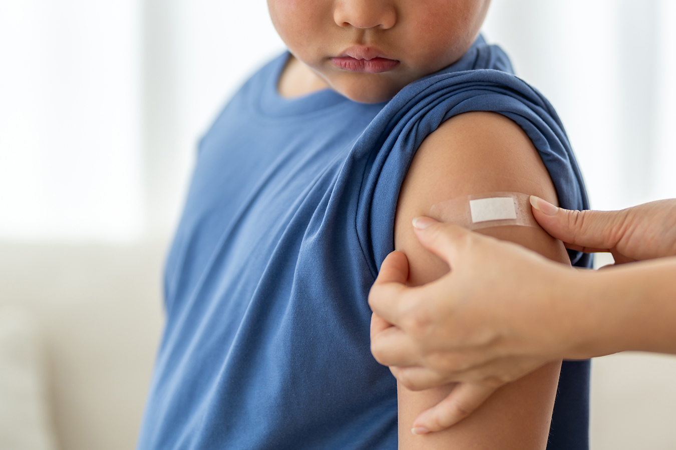 Child with a bandage on upper arm after vaccination.
