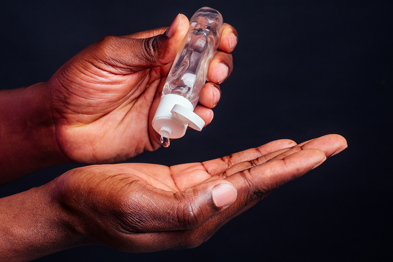 A close up of hands pouring hand sanitizer into an open palm