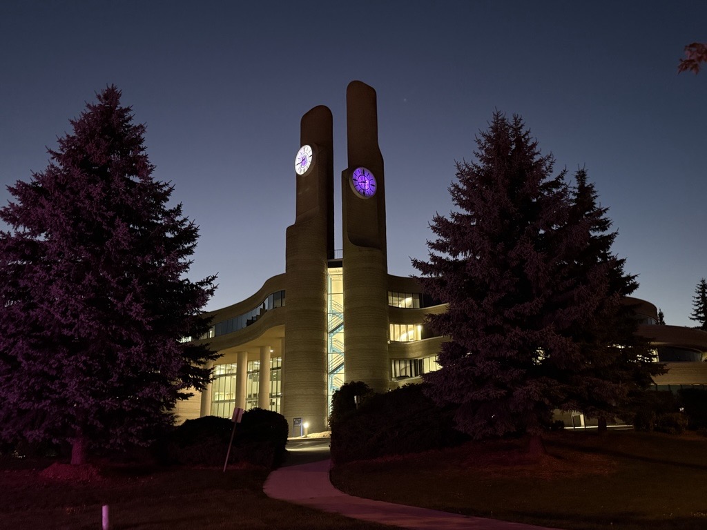 York Region Administrative Building clocktowers with clock faces lit up purple at nighttime.