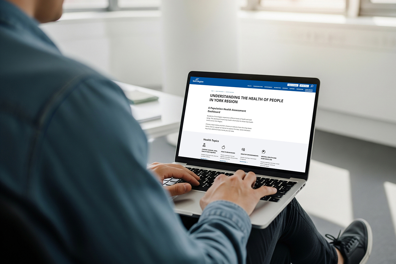 Person typing on a laptop open on a webpage with the heading "Understanding the Health of People in York Region"