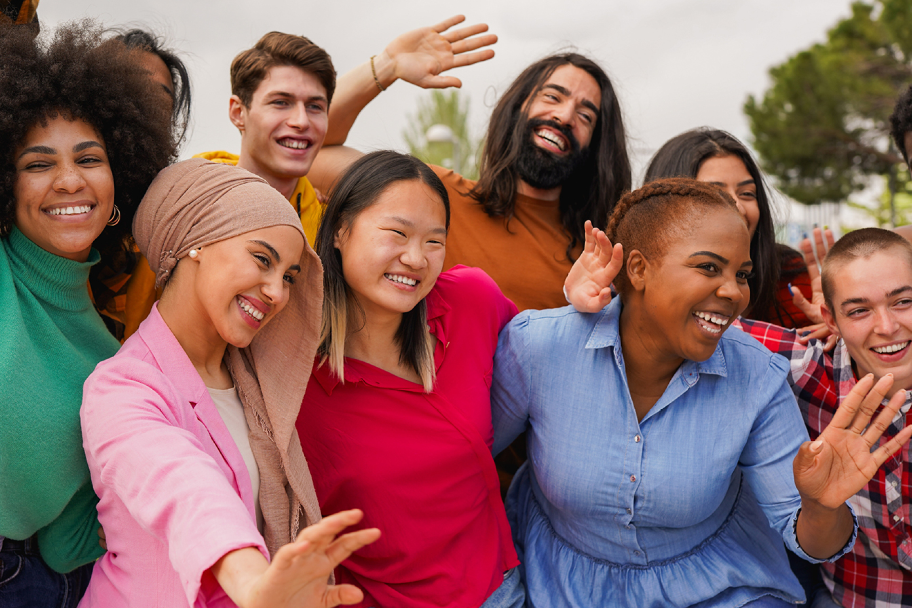 Group of people standing close together, some raising or waving their hands