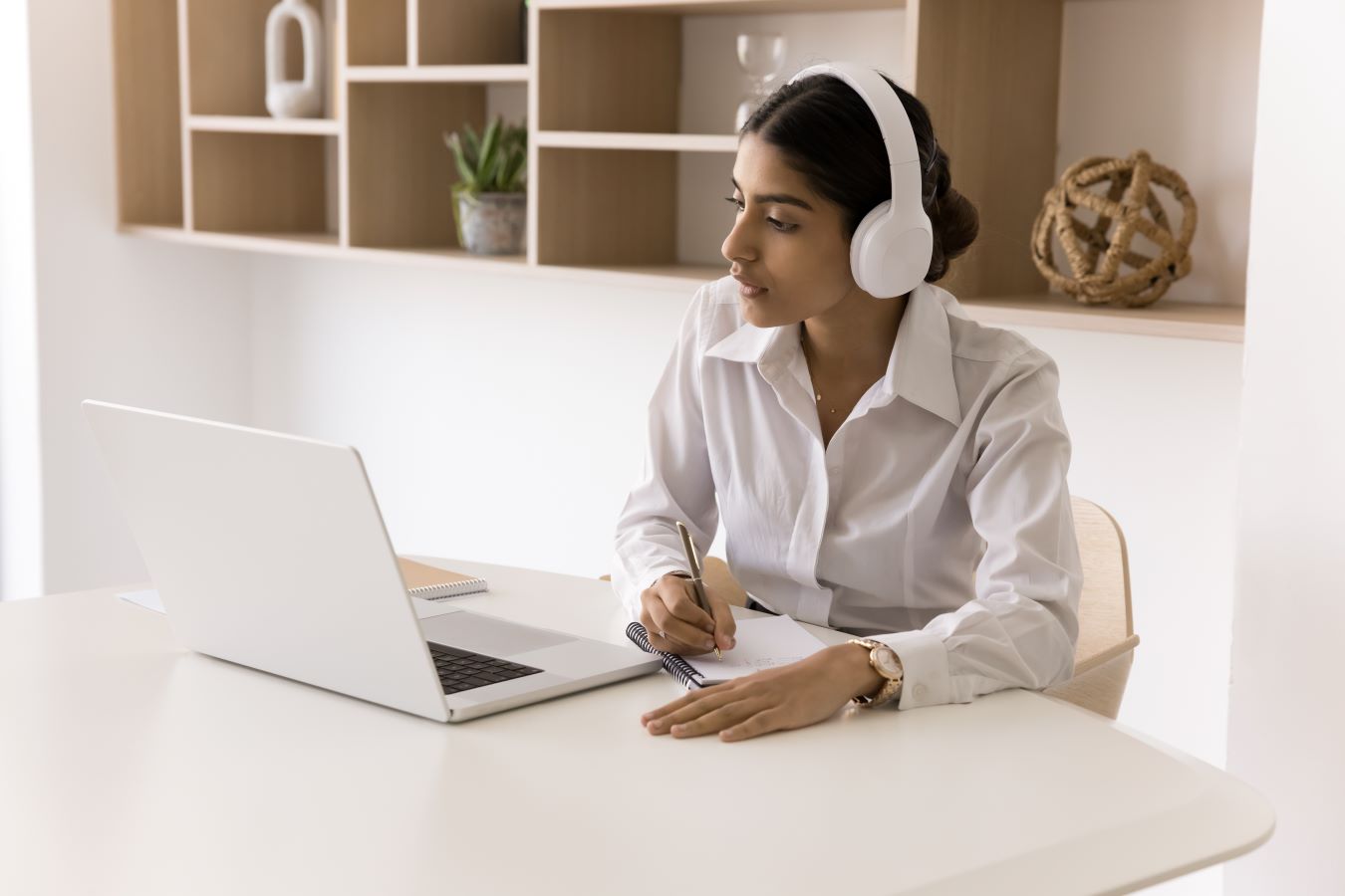 A person with headphones on listening to an online learning course