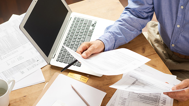 Person holding paperwork with laptop on table