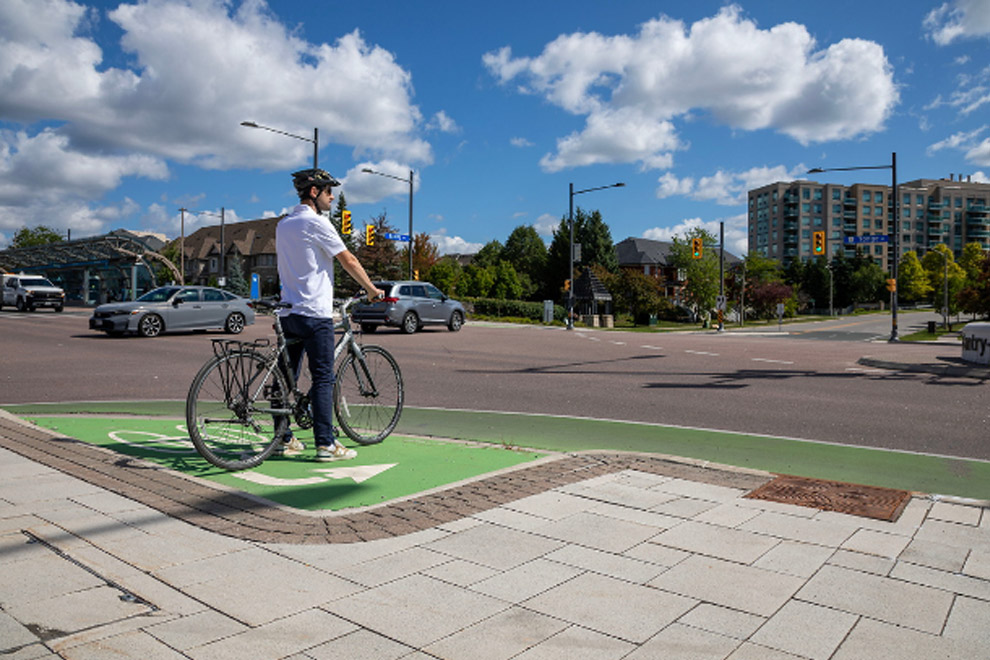 Person standing with bicycle in cycle lane.