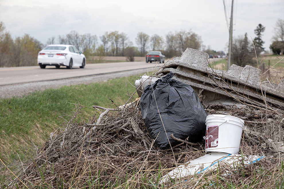 garbage on the side of the road as a car passes by