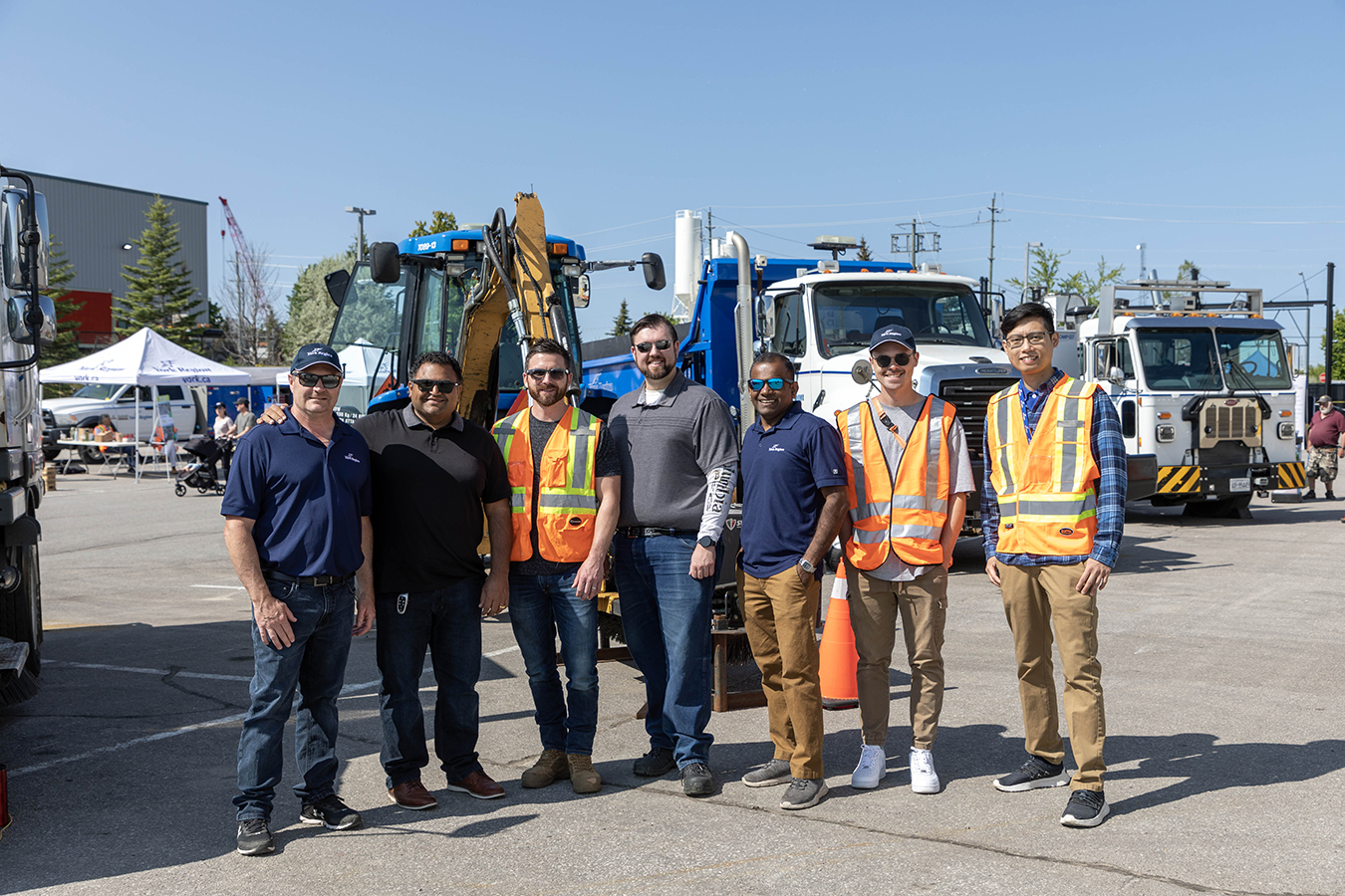 public works staff standing together in front of some heavy duty trucks
