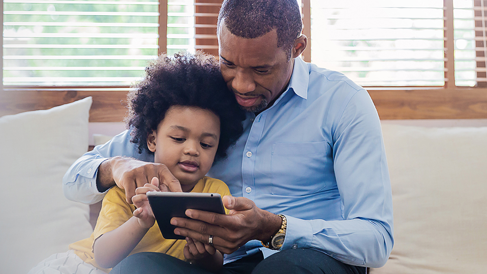 an adult and young child sitting together looking at a tablet