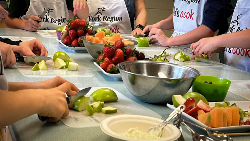a group of people slicing fruit on a countertop