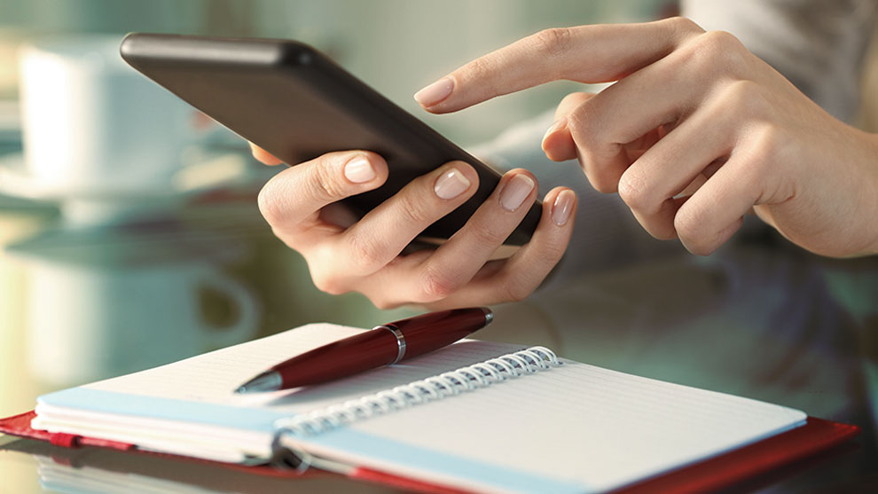 close up of hands holding a smart phone over an appointment book