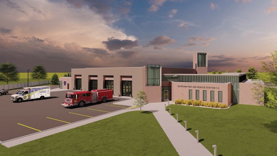 Architectural rendering of the Georgina Fire and Rescue Station 1-2 building, showing a modern fire hall with multiple vehicle bays, a fire truck and ambulance parked outside, landscaped grounds, and a cloudy sunset sky.