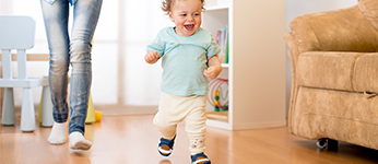 A toddler running in the house followed by his mother